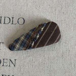 Detail of plaid and striped fabric patchwork hair clip with fringe stitching detail