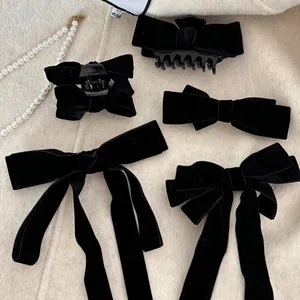 Detailed set of black velvet bow hair clips and claw clips on a soft cream background