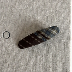 Detail view of retro plaid fringe hair clip with brown and blue-green fabric patchwork