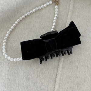 Top view of elegant black velvet bow hair claw clip on soft beige wool background
