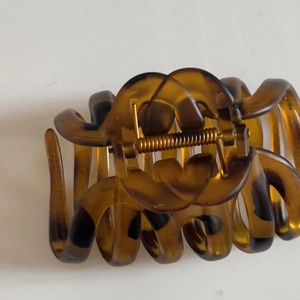 Detailed view of tortoise shell hair claw with amber pattern and strong metal spring