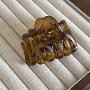 Close-up of tortoise shell hair claw clip with gold metal spring on a jewelry tray