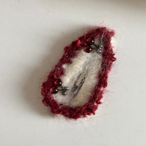 Detail of white plush hair clip with red crochet trim and beaded cherry accents