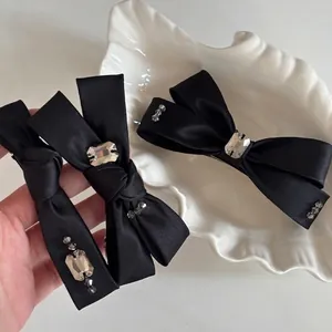 Barrettes à cheveux élégantes en satin noir avec cristaux et perles sur plateau blanc