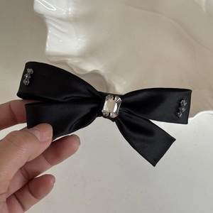 Vue détaillée du nœud en satin noir avec décoration en cristal et perles à facettes