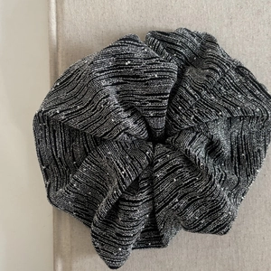 Detail of a large scrunchie featuring black fabric with silver metallic stripes and shimmering texture