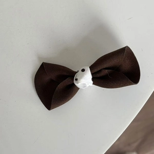 Detail of a brown ribbed ribbon hair clip with a stylish polka dot fabric centerpiece