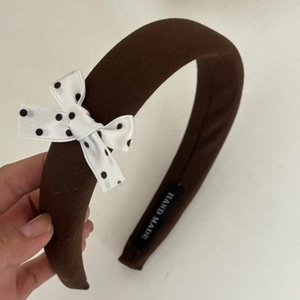 Detail of coffee brown padded headband with black and white polka dot bow and label