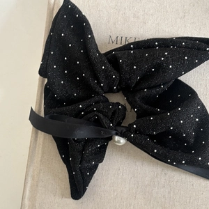 Macro shot of large black bow scrunchie with silver studs and elegant center pearl