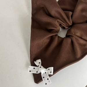 Detailed macro view of caramel polka dot bow hair scrunchie with textured twill fabric