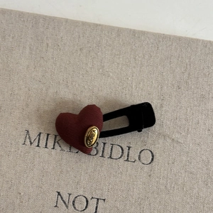 Detail of red fabric heart hair clip with gold Korea emblem on a black bobby pin