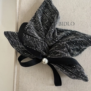 Close-up of black and silver textured fabric bow with a faux pearl center decoration