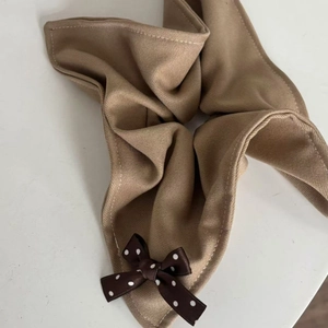 Detail of caramel latte fabric scrunchie with twill texture and polka dot bow decoration