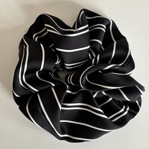 Detail eines großen schwarz-weiß gestreiften Haargummis mit weicher Chiffon-Textur