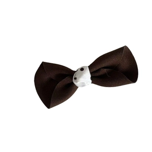 Caramel brown bow hair clip with white polka dot center on minimalist white background