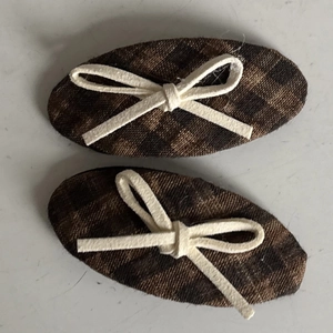 Detail view of plaid bow hair clips in brown check fabric with cream string bows