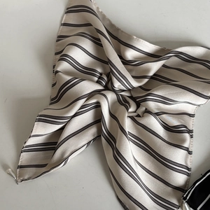 Detail eines gestreiften Satin-Haargummis mit elegantem Perlenanhänger und Glanzeffekt