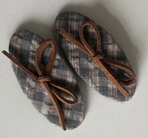 Macro view of blue checkered doll shoes with brown faux leather laces and bow tie detail