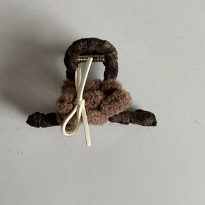 Detailed view of the brown plaid fabric hair claw clip with plush texture and cream bow