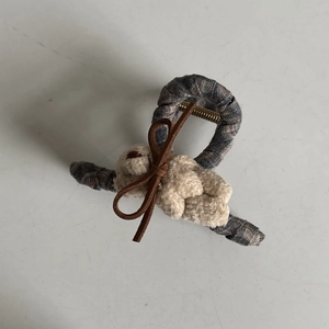 Detail of grey checkered hair claw clip featuring a plush white rabbit and brown bow tie