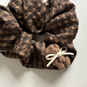 Detailed close-up of brown plaid scrunchie with cute plush bear and white bow tie