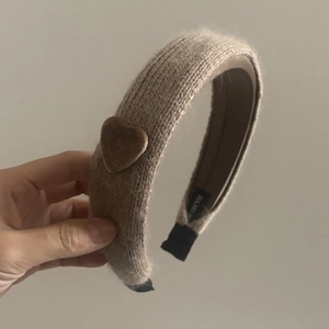 Detailaufnahme des handgefertigten Strickstirnbands mit Samtherz und Markenetikett