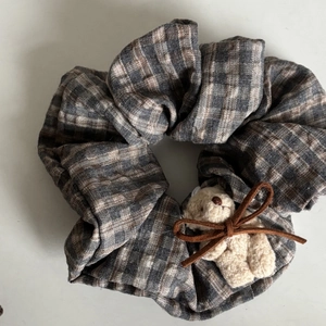 Detailed view of plaid scrunchie with a cute plush bear charm and suede bow accessory
