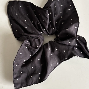 Detailed view of a black polka dot scrunchie with high-quality soft pleated fabric texture