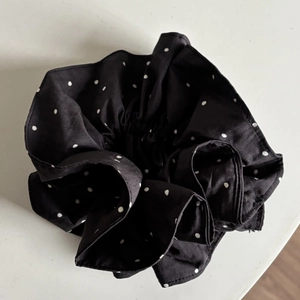 Detail of a large black scrunchie with white polka dots made of premium cotton fabric