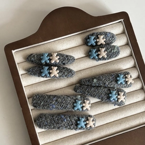 Cute blue and beige bear tweed fabric hair clips displayed on a wooden jewelry stand