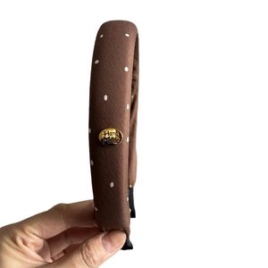 Brown polka dot headband with high volume padding and handmade gold oval charm detail