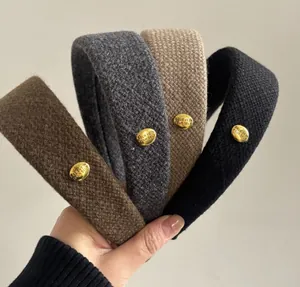 Detail of vintage fabric headband featuring a metallic gold button with engraved text
