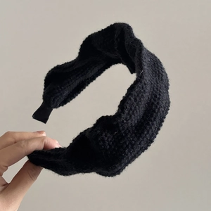 Close-up of black knitted headband with twist knot design and thick textured fabric