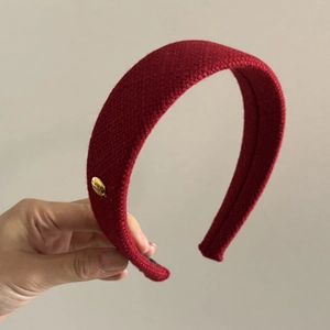 Detail of burgundy knitted headband with a decorative gold logo for a stylish look