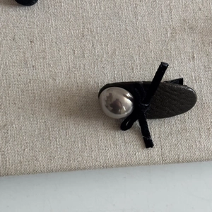 Detailed macro view of black lychee leather hair clip with silver bead and ribbon bow