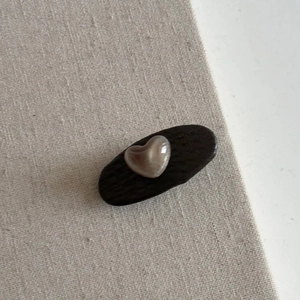 Detail view of heart shaped cat eye pearl embellishment on leather bow hair clip