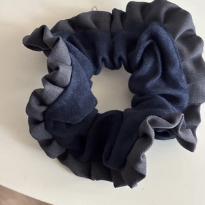 Detailed view of navy blue velvet hair scrunchie with contrasting grey ruffled trim