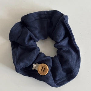 Detail of navy blue fabric hair scrunchie with wooden button and side label