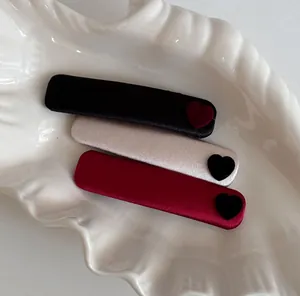 Detailed view of three satin velvet heart hair clips displayed in a white shell dish