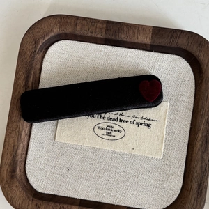 Elegant velvet red heart hair clip on black fabric base displayed on a wooden tray