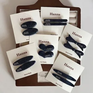 Barrettes en denim bleu avec lettrage argenté présentées sur un plateau à bijoux
