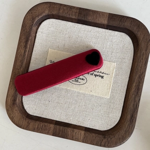 Close-up of red satin barrette with black flocked heart detail on a wooden tray
