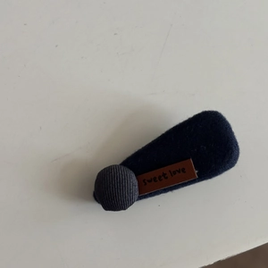 Detail of dark blue felt hair clip with corduroy button and sweet love leather label