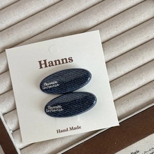 Lot de deux barrettes ovales en jean bleu marine avec logo argenté sur carte blanche