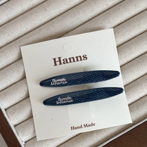 Détail de deux barrettes bleu marine texture denim avec lettrage argenté sur carte