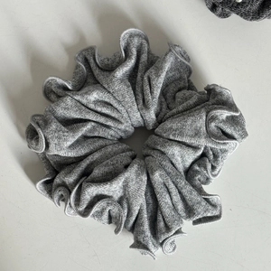 Gros plan du chouchou en maille gris chiné montrant la texture douce et le bord ondulé