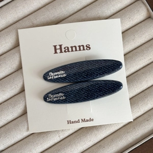 Vue macro détaillée de deux barrettes en denim bleu avec lettrage argenté sur une carte cadeau