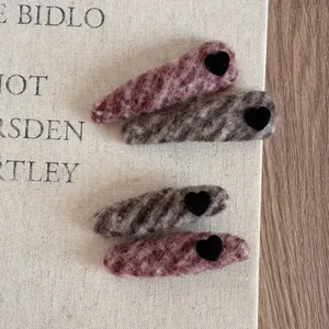 Close-up of four French velvet heart hair clips in pink and taupe on a wooden desk