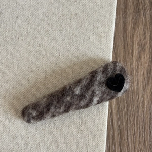 Close-up of wool felt heart hair clip with black velvet heart on beige canvas background