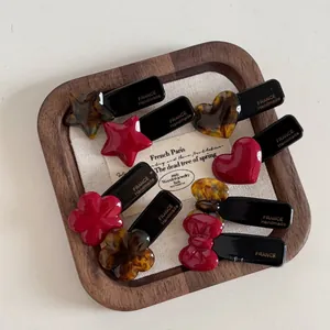 Detailed macro view of assorted red and tortoiseshell acetate hair clips on a wood tray